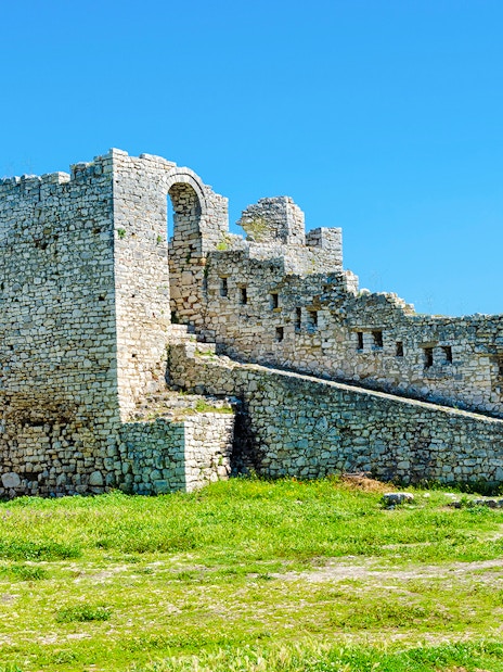 Berat Castle stone walls and archway under a clear blue sky in Albania.