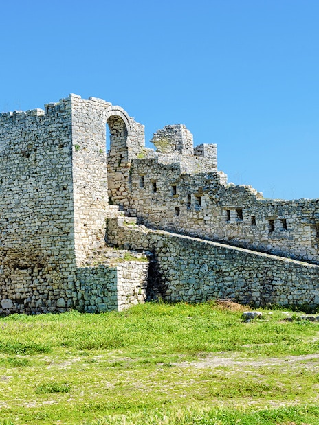 Berat Castle stone walls and archway under a clear blue sky in Albania.