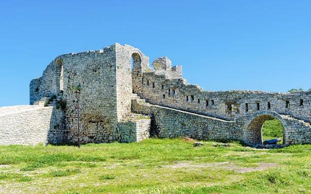 Berat Castle stone walls and archway under a clear blue sky in Albania.