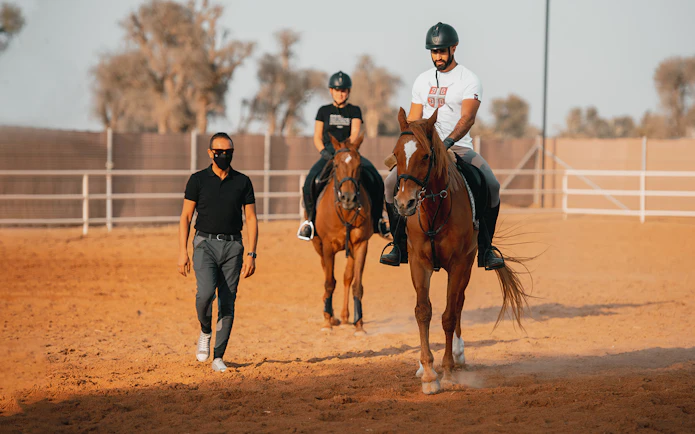 Horseback riders guided by an instructor at Mleiha Arena.