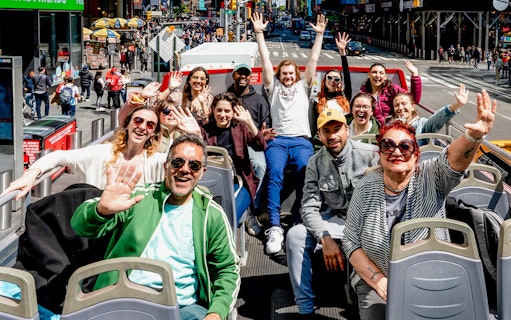 People waving on a New York Hop On Hop Off bus tour.