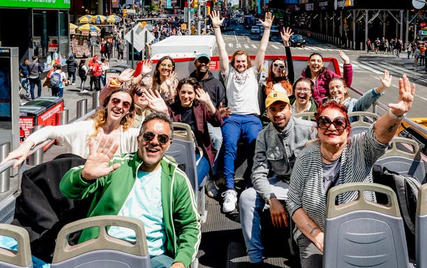 People waving on a New York Hop On Hop Off bus tour.