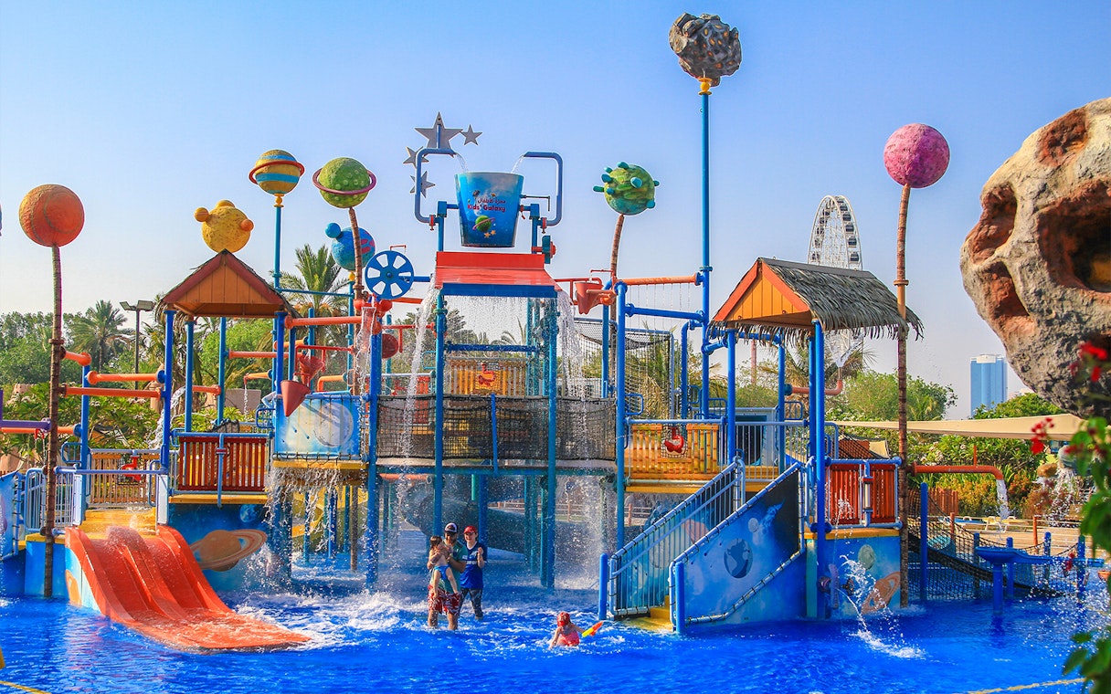 Children playing at Al Montazah Water Park with colorful slides and water features.