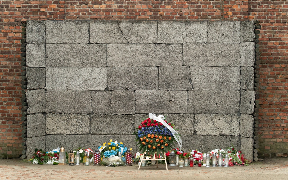 Memorial wall with flowers and candles at Auschwitz-Birkenau Concentration Camp.