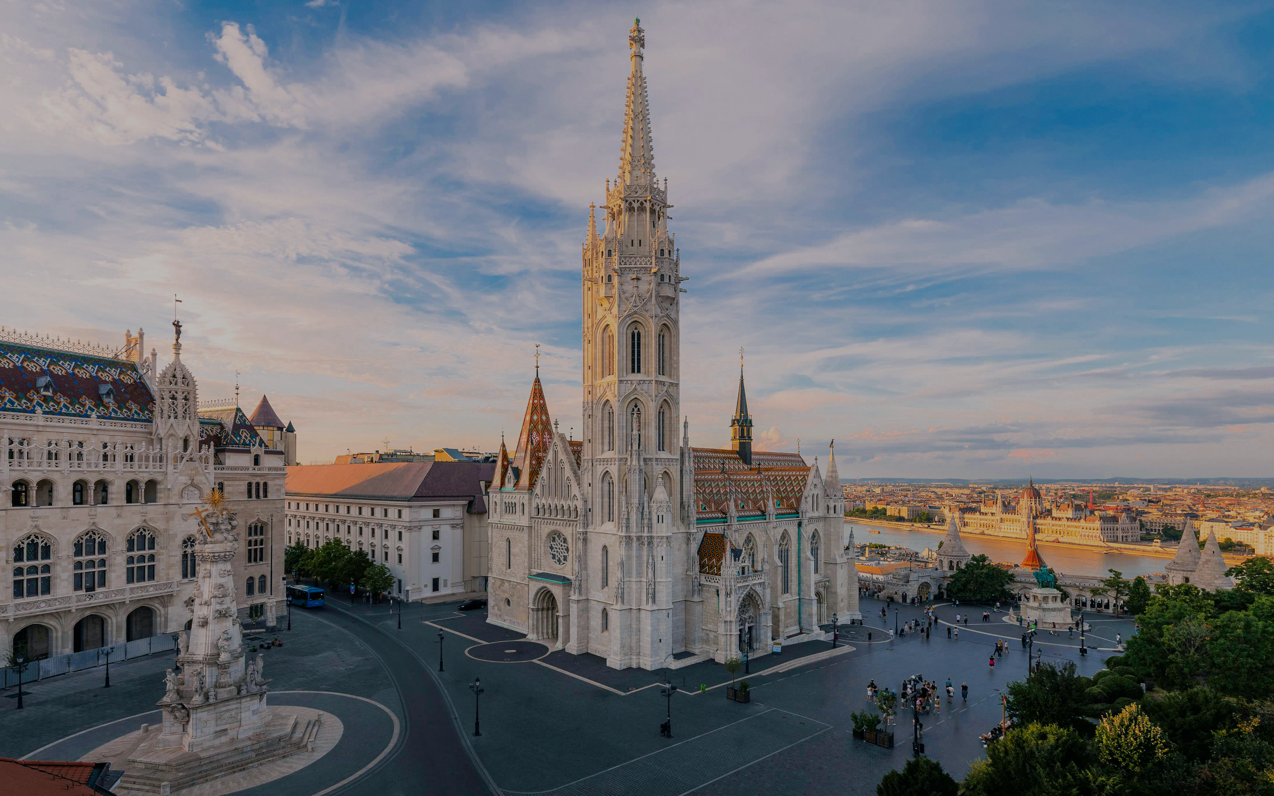 Matthias Church and Fisherman's Bastion in Budapest at sunset, overlooking the Danube River.