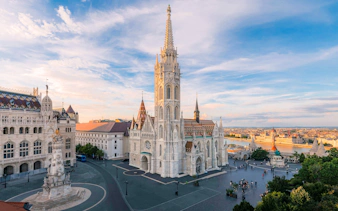 Matthias Church and Fisherman's Bastion in Budapest at sunset, overlooking the Danube River.