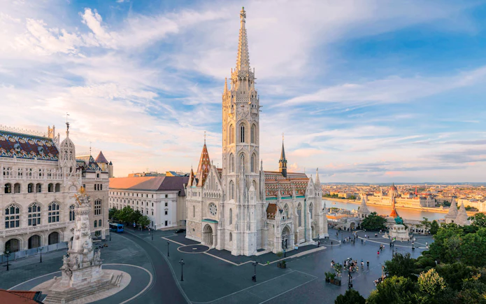 Matthias Church and Fisherman's Bastion in Budapest at sunset, overlooking the Danube River.