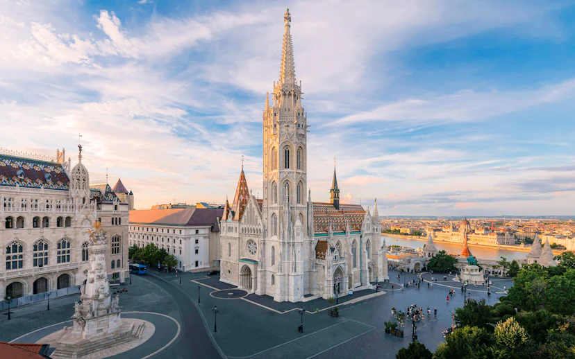 Matthias Church and Fisherman's Bastion in Budapest at sunset, overlooking the Danube River.