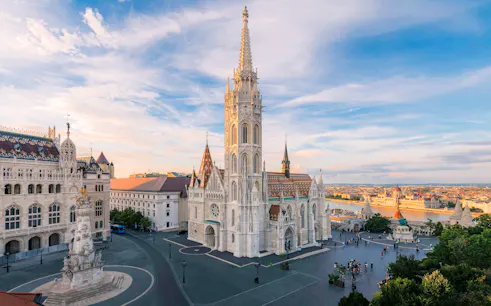 Matthias Church and Fisherman's Bastion in Budapest at sunset, overlooking the Danube River.