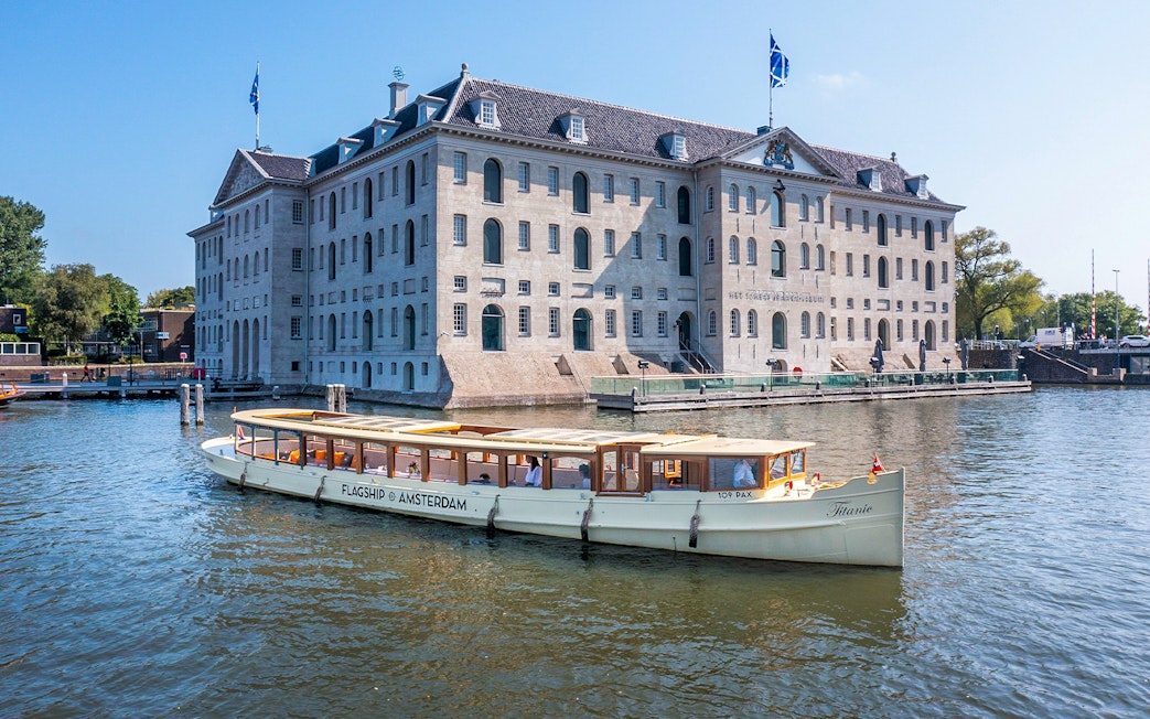 Canal boat cruising past the National Maritime Museum in Amsterdam.