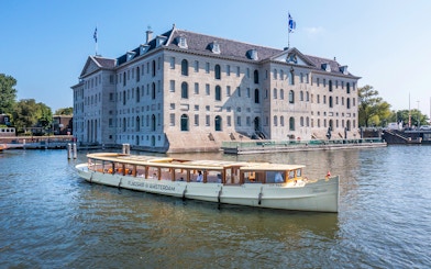 Canal boat cruising past the National Maritime Museum in Amsterdam.