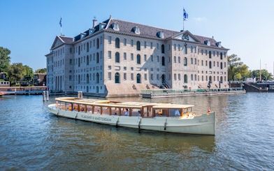 Canal boat cruising past the National Maritime Museum in Amsterdam.