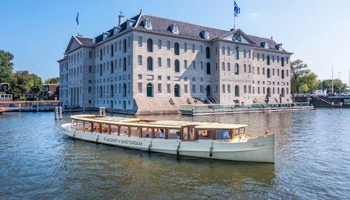 Canal boat cruising past the National Maritime Museum in Amsterdam.