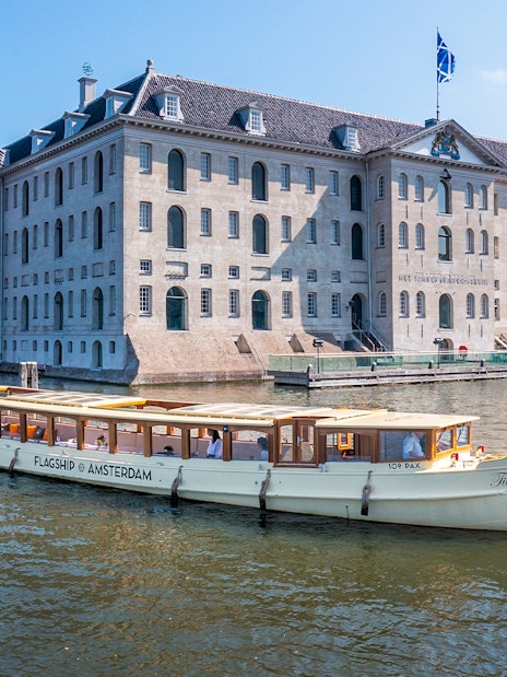 Canal boat cruising past the National Maritime Museum in Amsterdam.