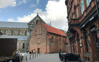 Historic brick buildings on a street in Malmo, Sweden, with outdoor seating.