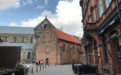 Historic brick buildings on a street in Malmo, Sweden, with outdoor seating.