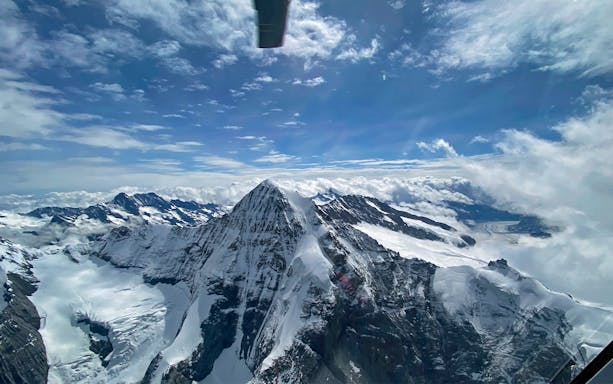Aerial view of snow-covered peaks during a private helicopter flight over the Swiss Alps.