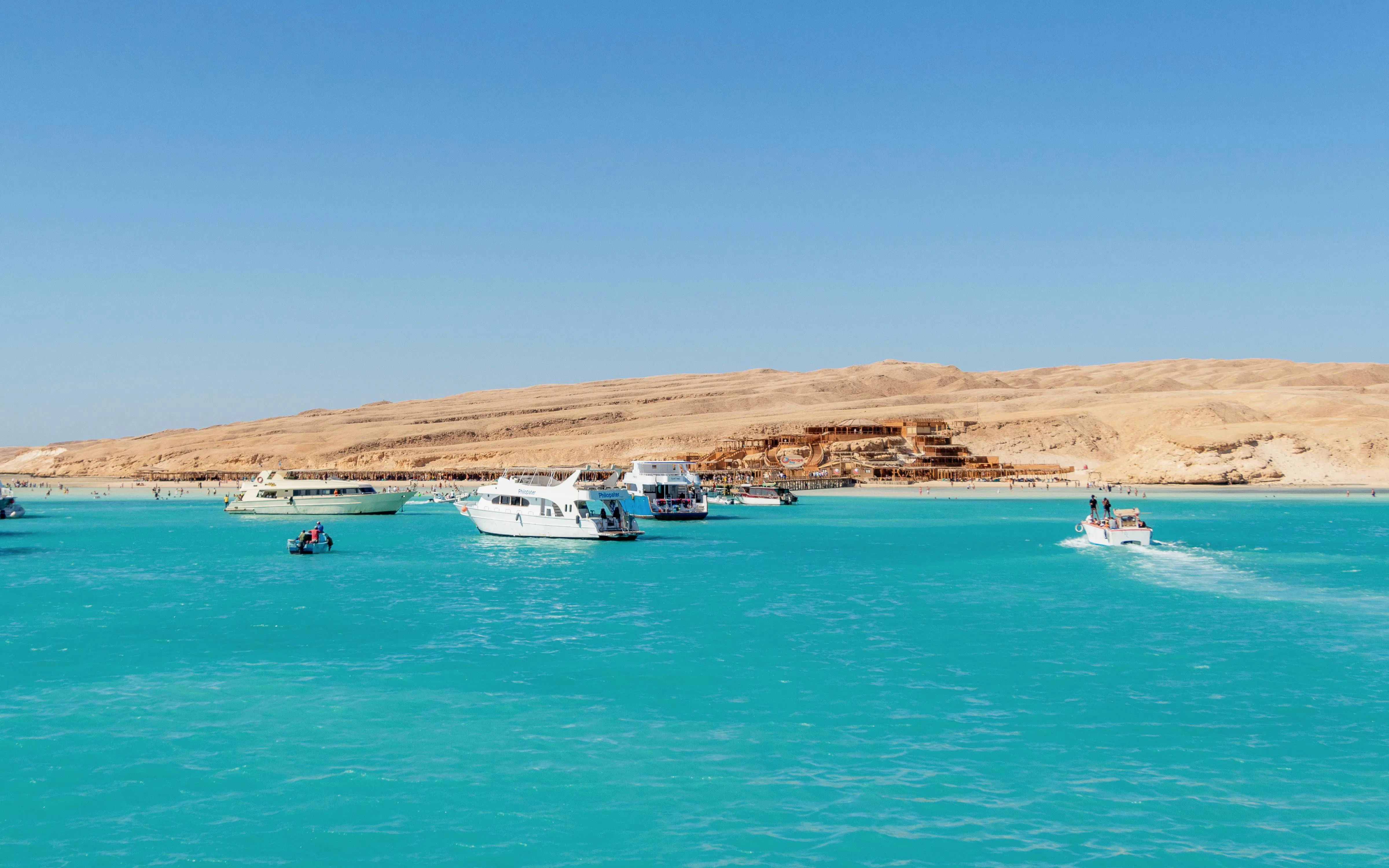 Boats with tourists on azure waters near Orange Bay Beach, Hurghada, Egypt.