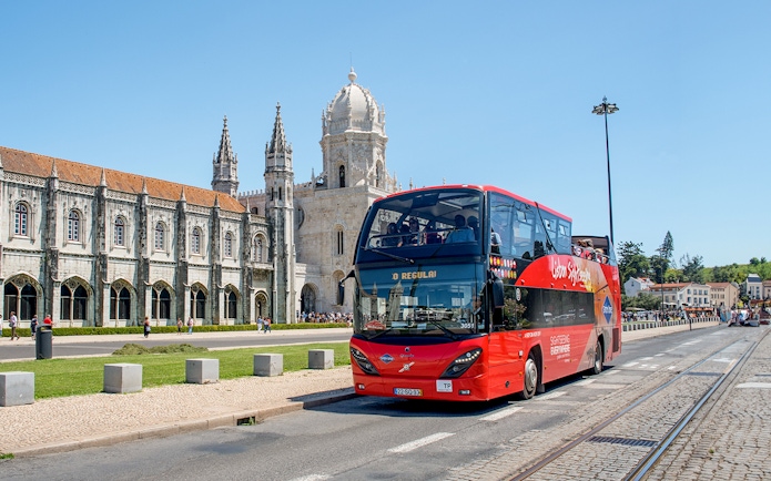 Red double-decker bus in front of Jerónimos Monastery, Lisbon.