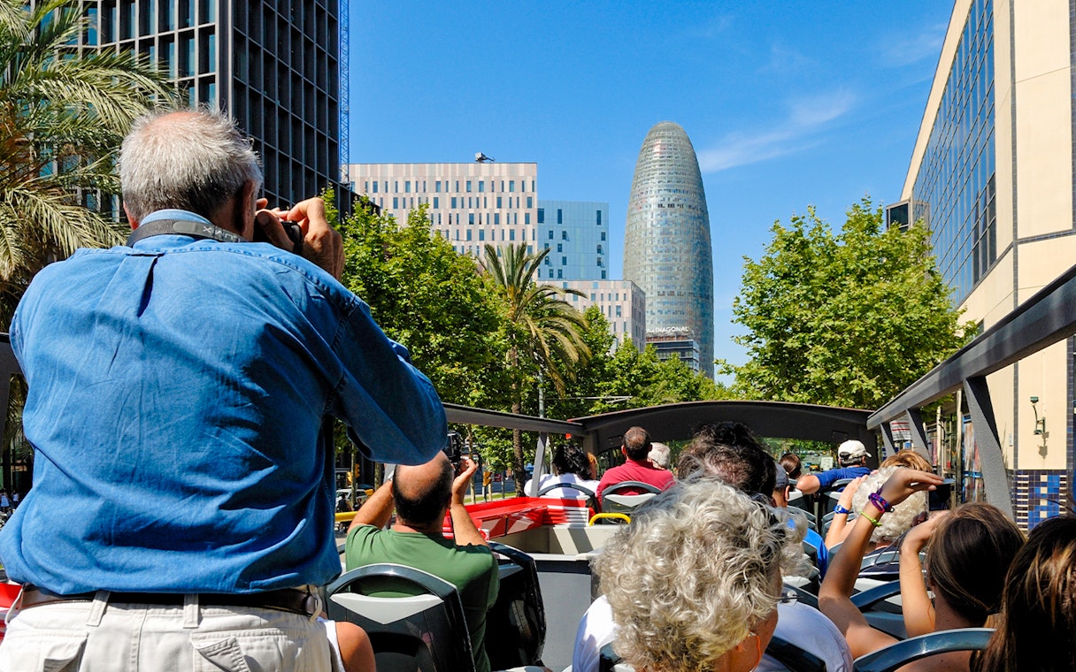 Tourists on Barcelona hop-on hop-off bus viewing Torre Glòries.