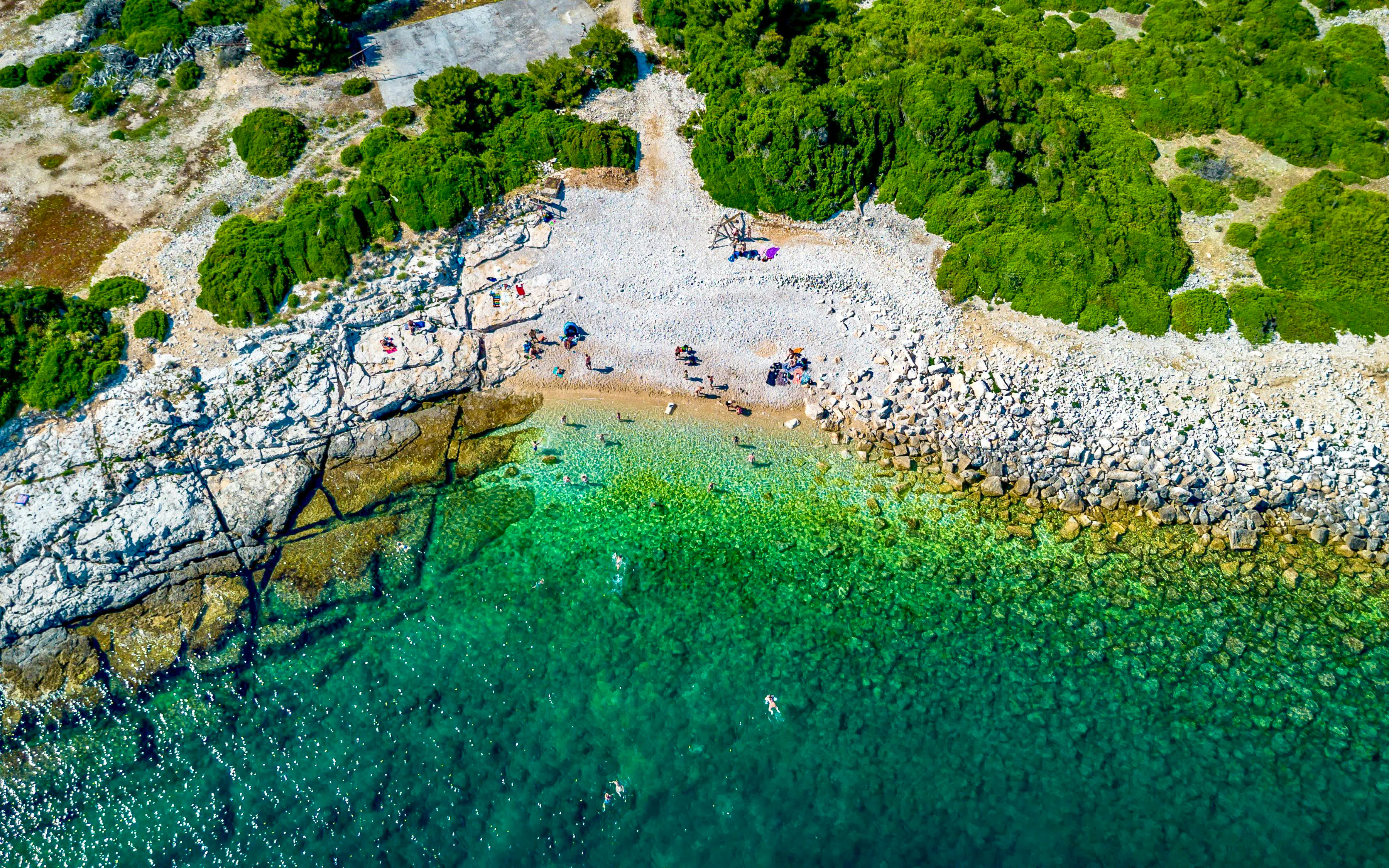 Aerial view of Brijuni National Park beach with swimmers and rocky shoreline near Pula.