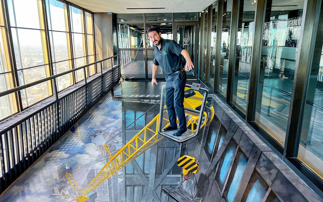 Man standing on a 3D art crane at Chicago 360 Observation Deck.