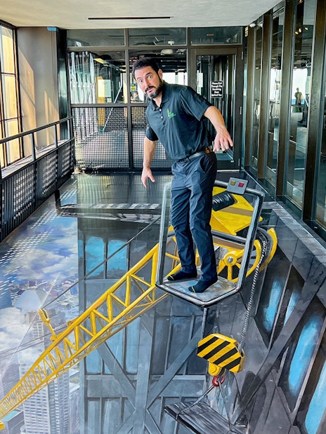 Man standing on a 3D art crane at Chicago 360 Observation Deck.