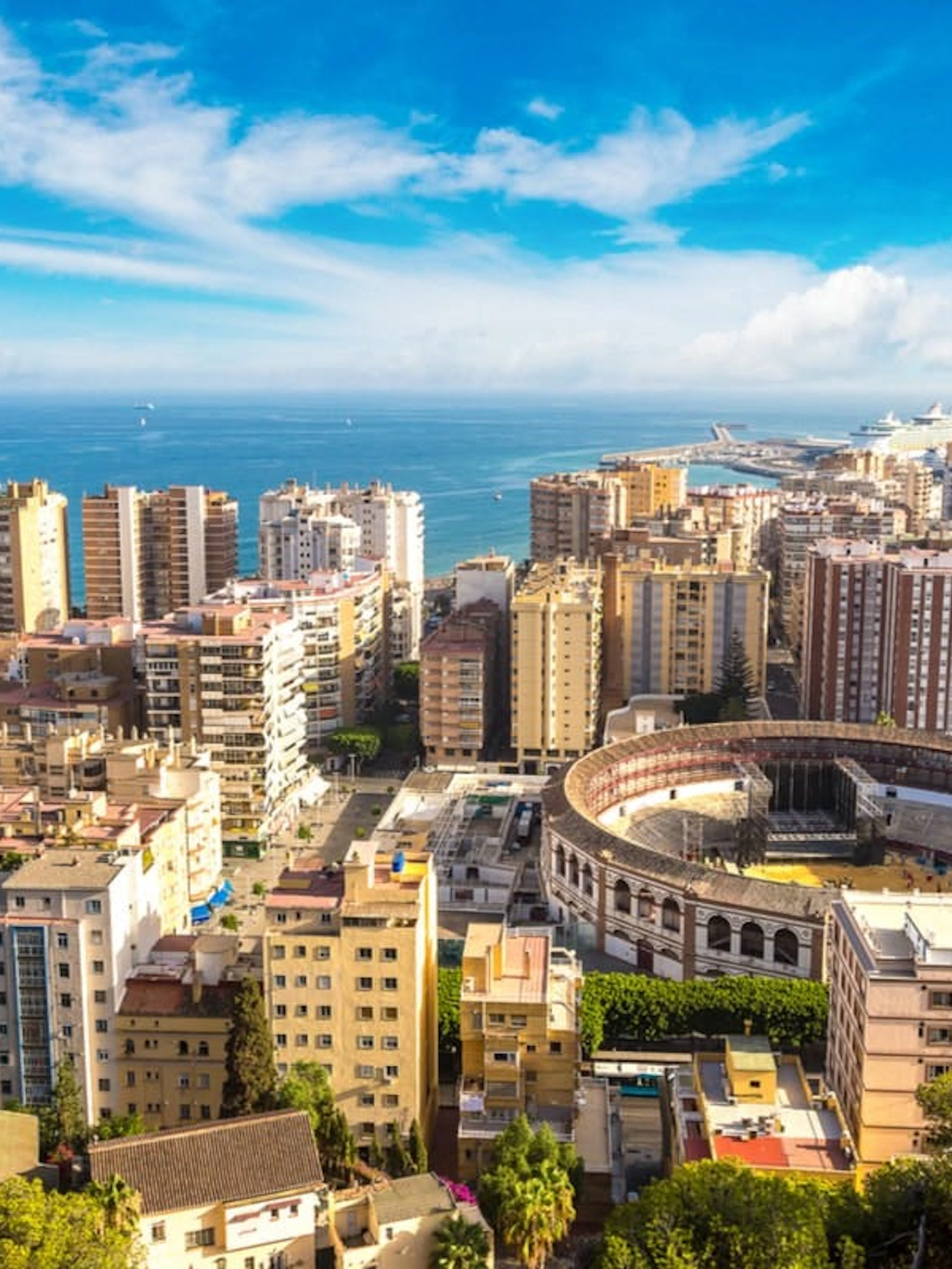 Aerial view of Malaga cityscape with the bullring and harbor in the background.