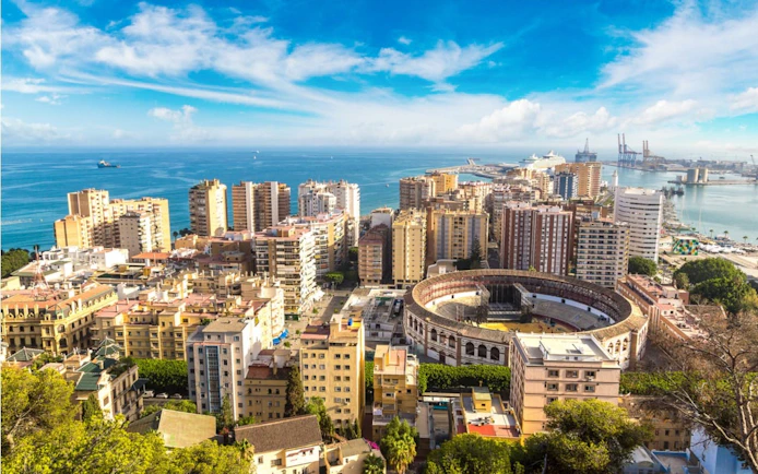 Aerial view of Malaga cityscape with the bullring and harbor in the background.