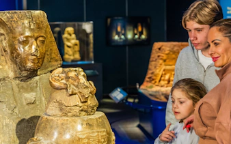 Family observing ancient Egyptian artifacts at Ramses and the Pharaohs' Gold exhibition.