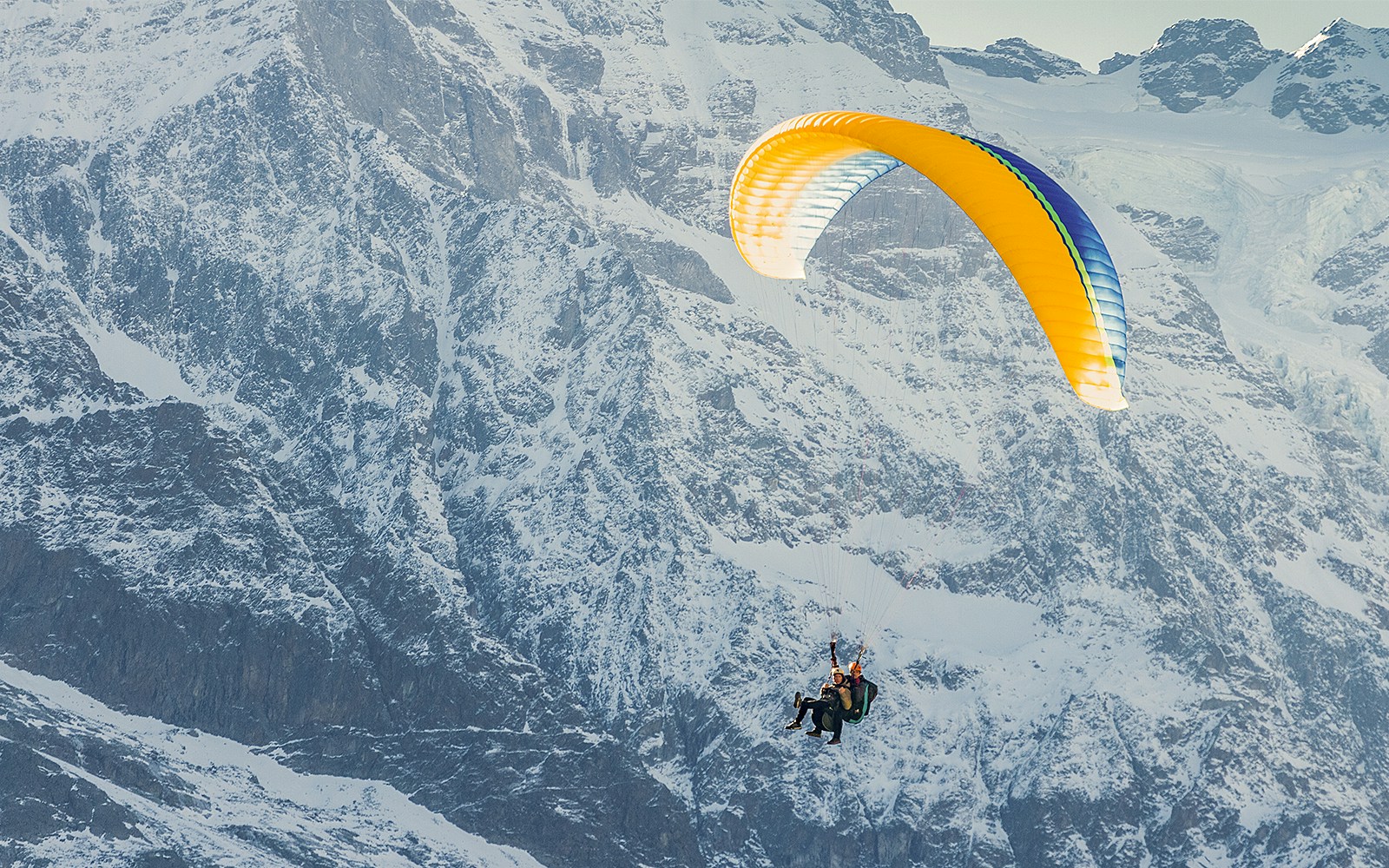 Paragliding over snowy mountains in Grindelwald First, Switzerland.