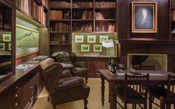 Graham's Port Lodge tasting room with leather chairs and wine bottles on table.
