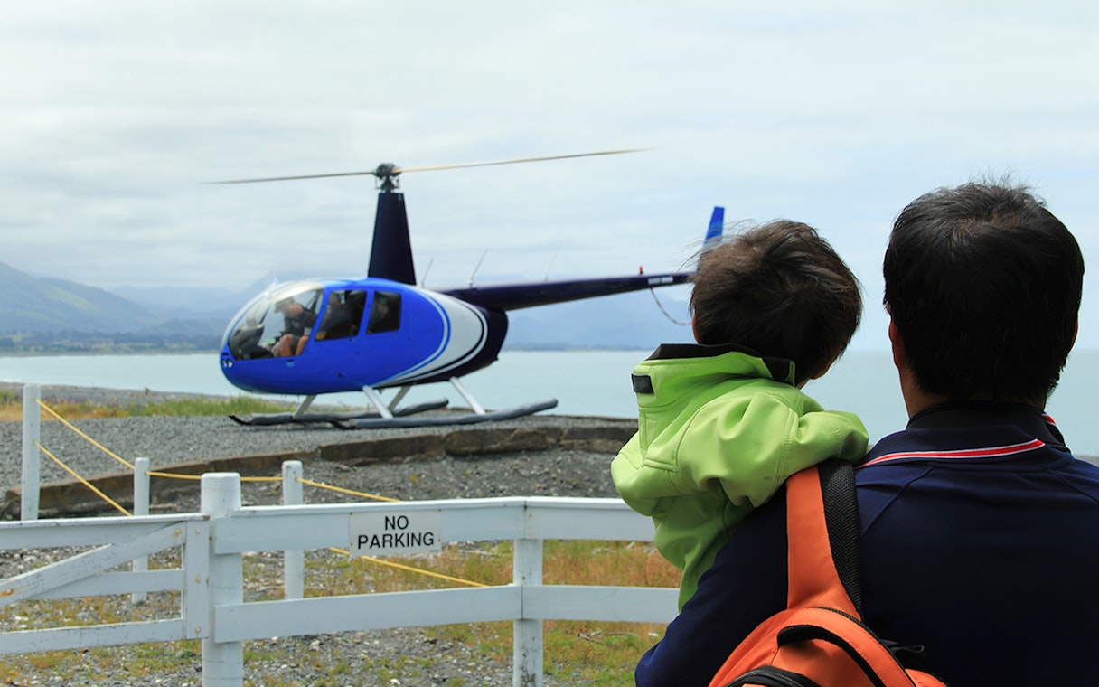 Father and son watching helicopter take off for whale watching in Kaikoura.