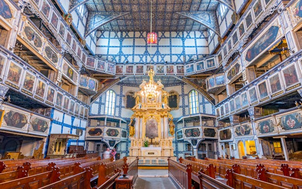 Interior of the Church of Peace in Świdnica, featuring ornate wooden galleries and altar.
