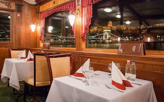 Interior dining area of New Year’s Eve Cruise in Budapest with view of illuminated cityscape.