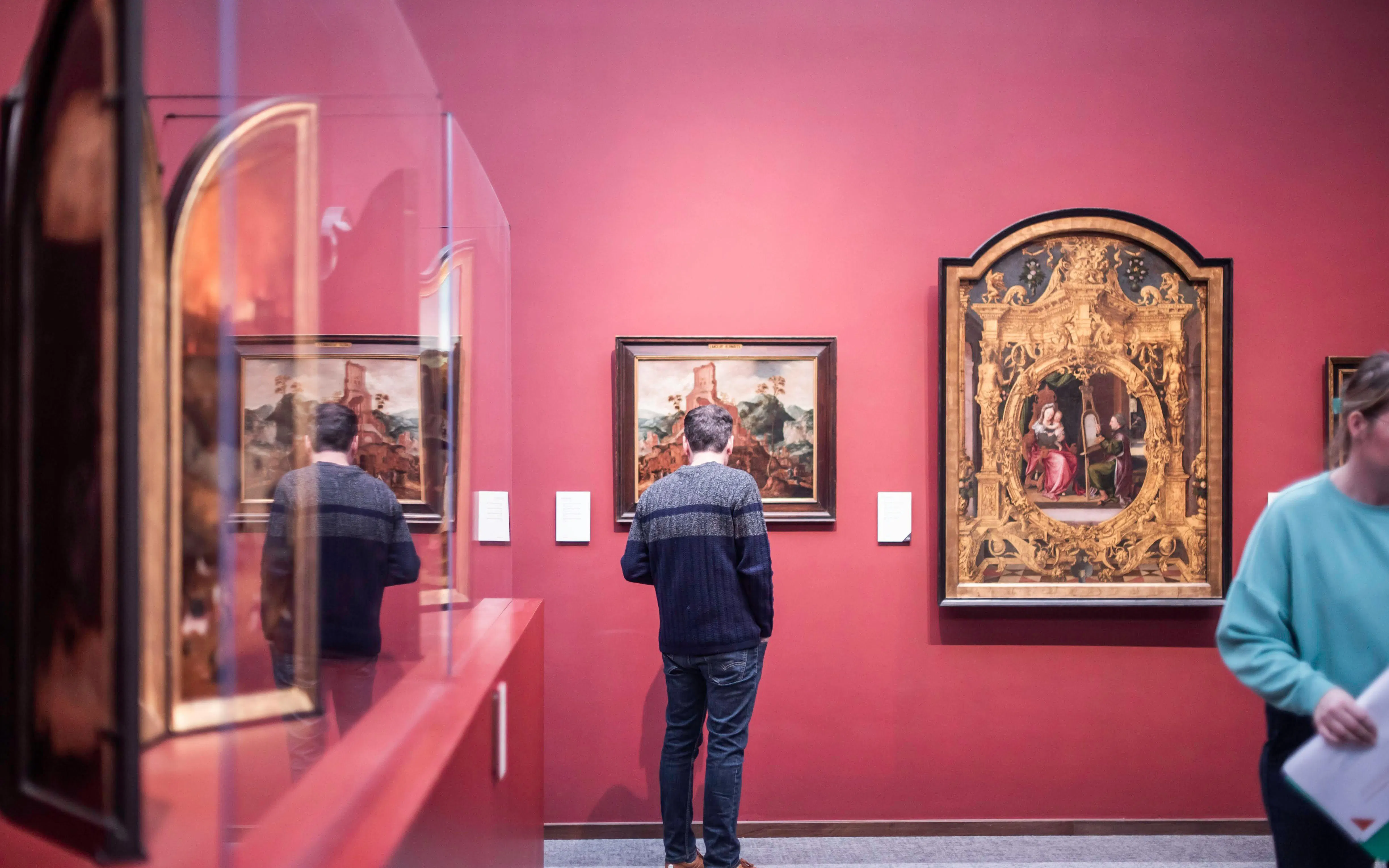 Visitor admiring paintings at Groeningemuseum, Bruges.
