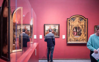 Visitor admiring paintings at Groeningemuseum, Bruges.