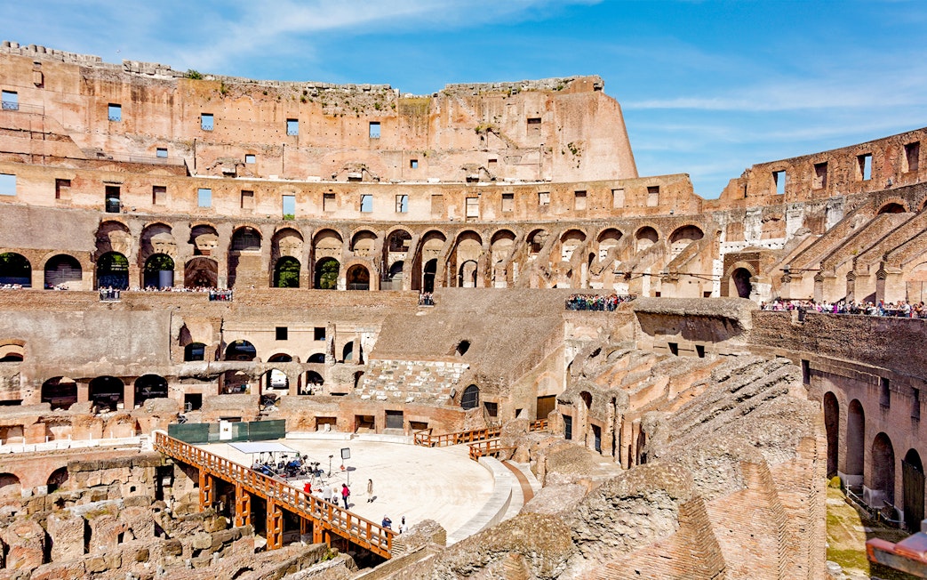 Tour group exploring the Colosseum Arena in Rome, viewing underground chambers and learning gladiator history.