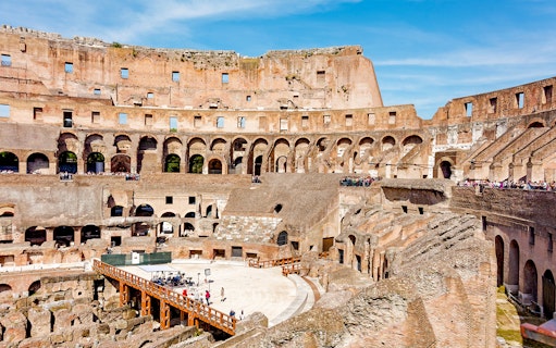 Tour group exploring the Colosseum Arena in Rome, viewing underground chambers and learning gladiator history.