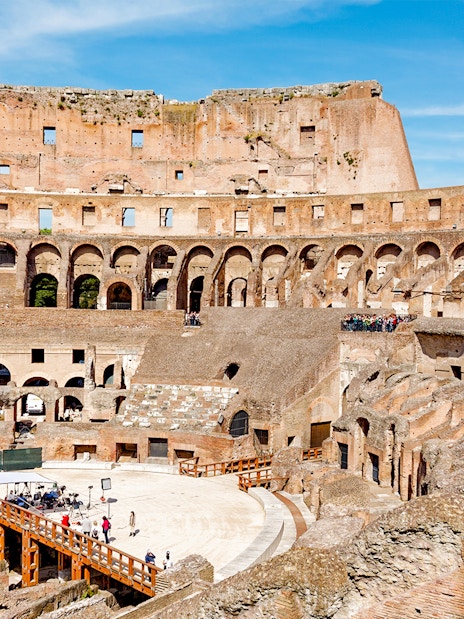 Tour group exploring the Colosseum Arena in Rome, viewing underground chambers and learning gladiator history.