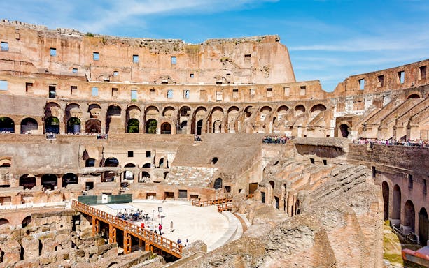 Tour group exploring the Colosseum Arena in Rome, viewing underground chambers and learning gladiator history.