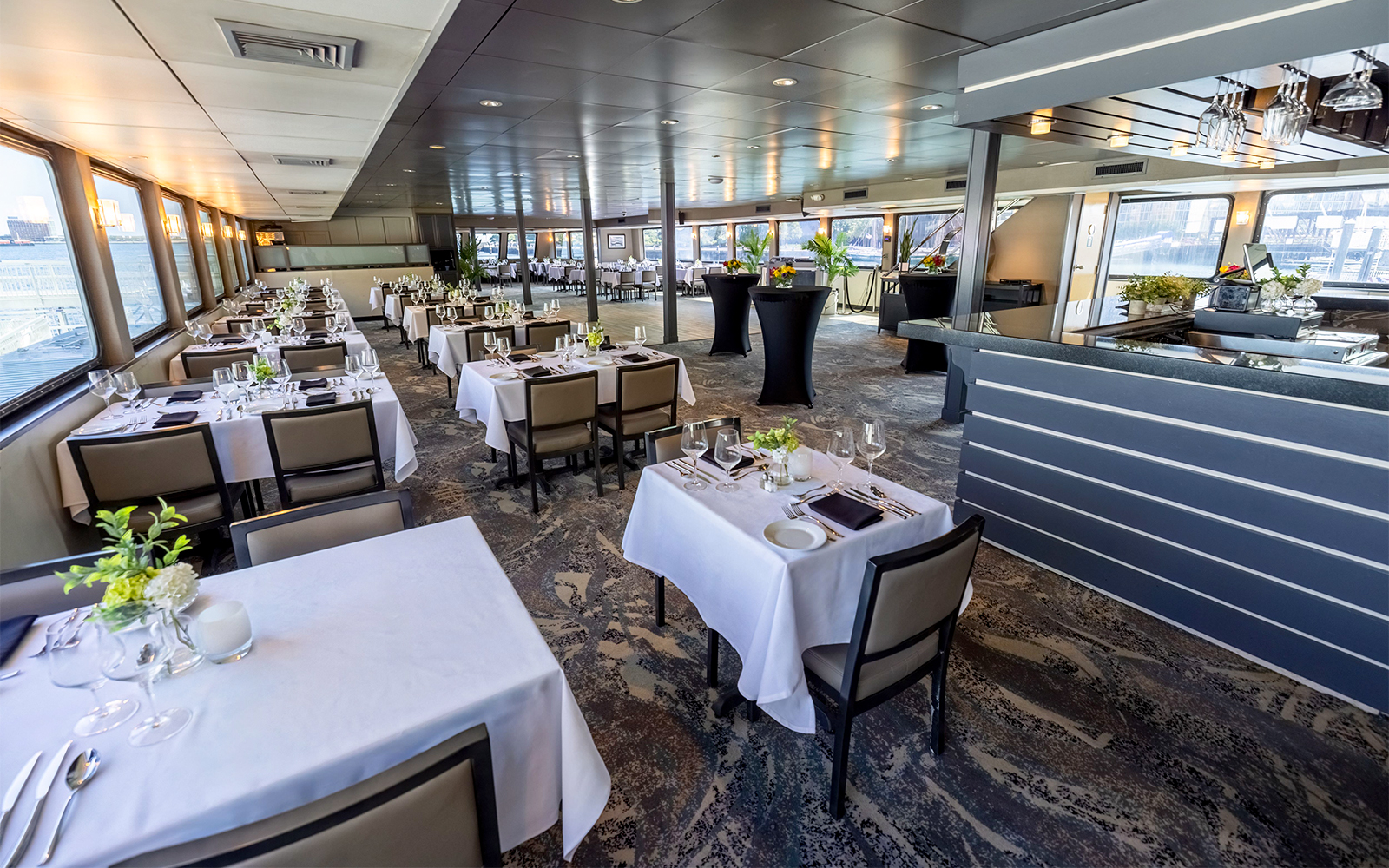 Dining area set for Boston Premier Lunch Cruise with tables and panoramic windows.