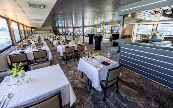 Dining area set for Boston Premier Lunch Cruise with tables and panoramic windows.