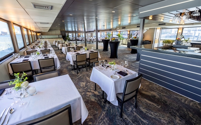Dining area set for Boston Premier Lunch Cruise with tables and panoramic windows.