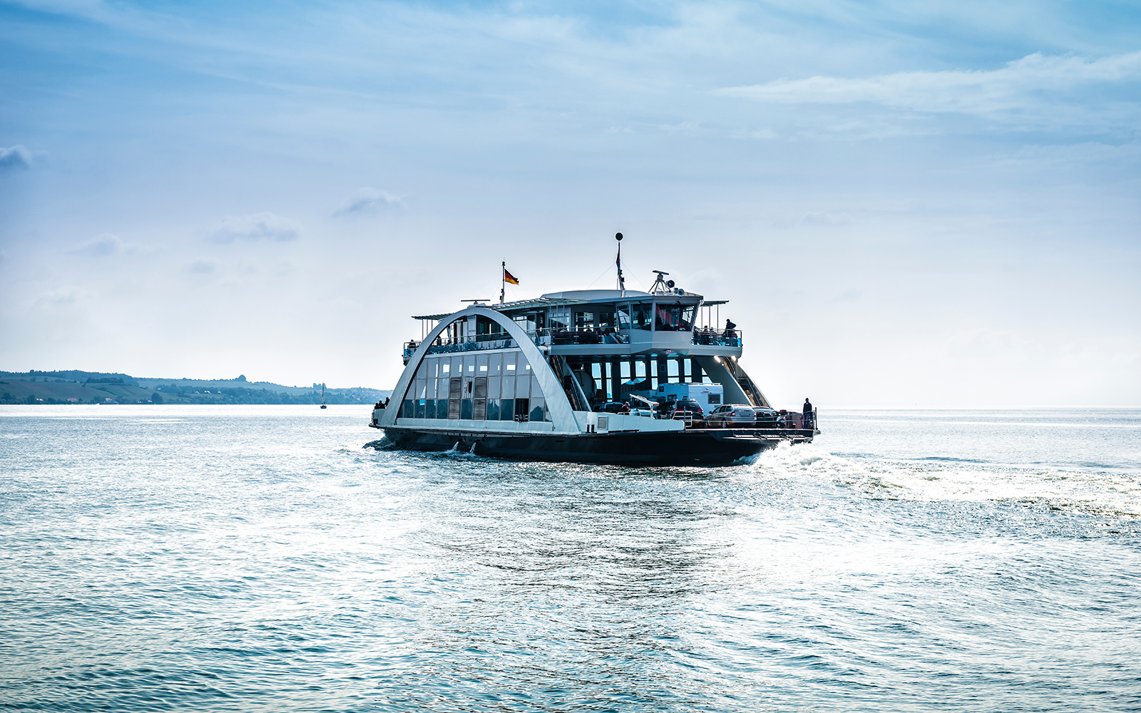 Ferry cruising on a calm sea near Blue Planet Aquarium, with distant shoreline in view.