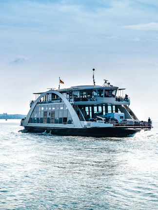 Ferry cruising on a calm sea near Blue Planet Aquarium, with distant shoreline in view.