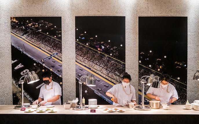 Chefs preparing dishes in front of Singapore Grand Prix track backdrop, Formula 1 Hospitality Package.