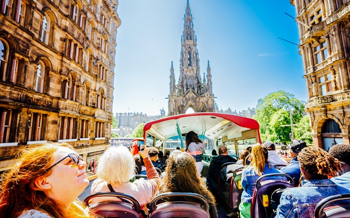 Open-top bus tour passing the Scott Monument in Edinburgh.