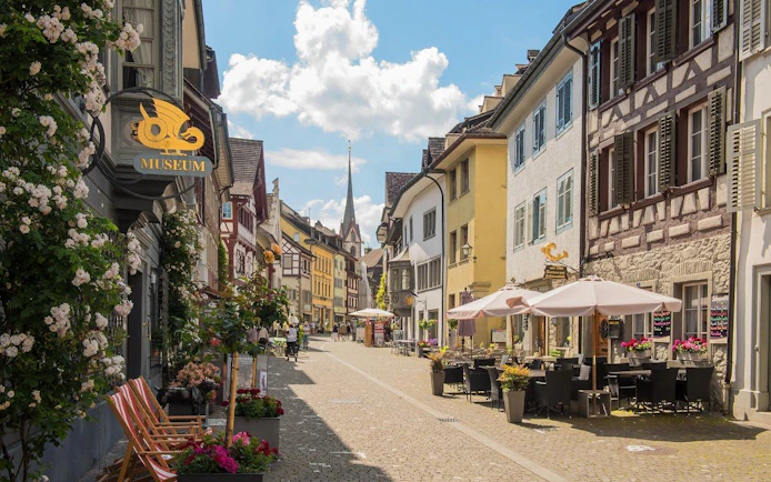 Stein am Rhein old town street with outdoor cafes and Lindwurm Museum sign.