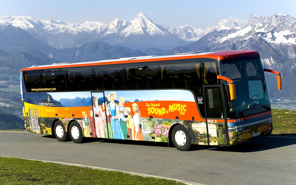 Original Sound of Music tour bus with mountain backdrop in Salzburg, Austria.